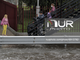 Passers-by descend stairs from a bridge under heavy rain in Mexico City where there were several floods in the Coyoacán, Tlalpan, Xochimilco...