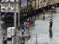 Long distance train passengers walk through the flooded railway tracks due to heavy rainfall in Tikipara railway carshed area, West Bengal,...