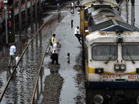 Long distance train passengers walk through the flooded railway tracks due to heavy rainfall in Tikipara railway carshed area, West Bengal,...