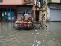A worker seats on a LPG gas cylinder van amidst a flooded street in Kolkata , India , on 30 July 2021 .LPG gas cylinder prices were hiked ov...