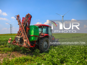 Wind turbines are seen next to a tractor working on the potato field in Gac village near Lancut, Podkarpackie voivodeship in Poland on July...