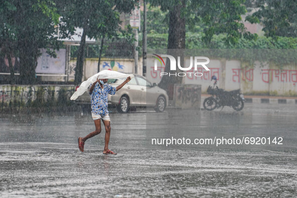 A man covers with polythene to protect himself as he walks during the rainfall in Dhaka, Bangladesh on July 31, 2021 