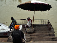 Indian boatmen sit under a wooden umbrella on the Banks of River Ganges at Assi Ghat in Varanasi on July 16,2015. (