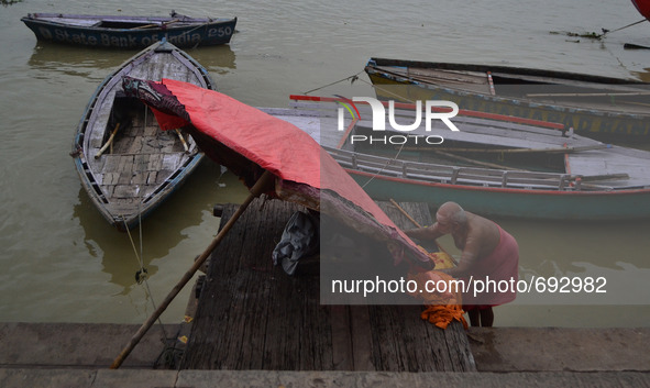 An indian priest set ups his wooden umbrella before rains on the banks of River Ganges at Assi Ghat,in Varanasi on July 16,2015.  