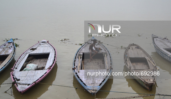 An indian boatman sit on his boat before rains at Dashashwa medha Ghat,on the banks of River Ganges,in Varanasi on July 16,2015. 