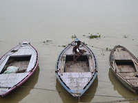 An indian boatman sit on his boat before rains at Dashashwa medha Ghat,on the banks of River Ganges,in Varanasi on July 16,2015. (