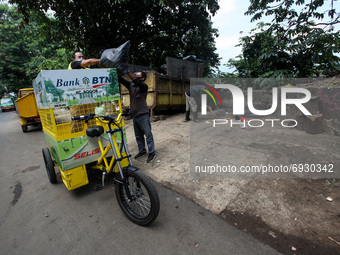 A Man throw rubbish non-organic into a eco-friendly electric bicycle cargo at a dumping site near settlement in Bogor, West Java, Indonesia,...