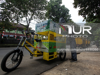 Workers throw rubbish non-organic into a eco-friendly electric bicycle cargo at a dumping site near settlement in Bogor, West Java, Indonesi...