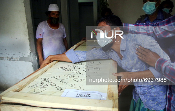 A wailing family member receives the coffin of a victim who had died in a devastating fire at Hashem Food and Beverage Factory in Narayangan...
