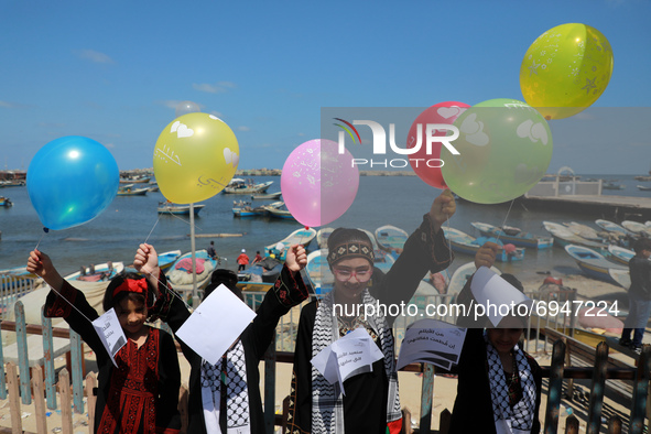 Palestinian children release balloons during a protest against the blockade on Gaza at the port of Gaza City on August 10 , 2021.  