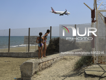 Children resting on Makenzy beach near Larnaca airport watch the plane land at Larnaca airport. Cyprus, Thursday, August 12, 2021. (