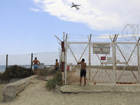 Vacationers on Makenzy Beach near Larnaca Airport watch the plane take off into the sky. Larnaca, Cyprus, Thursday, August 12, 2021. (