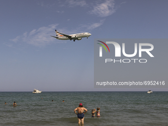 Vacationers swimming on Makenzy Beach near Larnaca Airport watch the plane land. Larnaca, Cyprus, Thursday, August 12, 2021. (