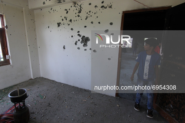 A boy looks at the wall of the damaged building where according to police a militant was killed in an encounter in south Kashmir's Kulgam ar...