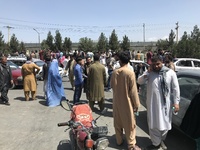 People struggle to cross the boundary wall of Hamid Karzai International Airport to flee the country after rumors that foreign countries are...