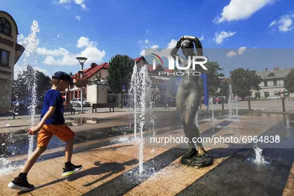 A boy is playing next to a fountain during a hot summer day in Andrychow, Poland on August 14, 2021. 