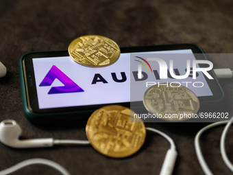 Audius logo displayed on a phone screen, headphones and representation of cryptocurrencies are seen in this illustration photo taken in Krak...