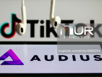 Audius logo displayed on a phone screen, TikTok logo displayed on a computer screen and headphones are seen in this illustration photo taken...