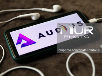 Audius logo displayed on a phone screen and headphones are seen in this illustration photo taken in Krakow, Poland on August 17, 2021. (