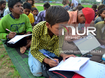 Indian children of slums study in a park,in Allahabad on July 19,2015.Indian students who prepare for competetive exams,educate children in...