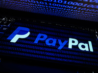 PayPal logo displayed on a phone screen is seen with binary code displayed on a laptop screen in this illustration photo taken in Krakow, Po...