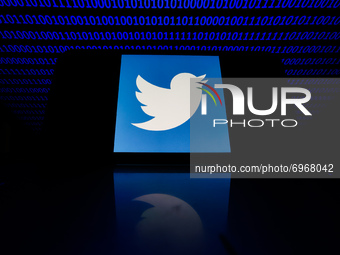 Twitter logo displayed on a phone screen is seen with binary code displayed on a laptop screen in this illustration photo taken in Krakow, P...