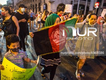 Protesters are seen with the flag of Afghanistan.Around a hundred women have participated in a feminist demonstration in front of the Unite...