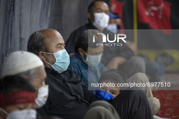 An Afghan refugee young boy wearing a protective face mask looks on while attending with his father at a Moharram mourning ceremony for pray...