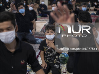 An Afghan refugee young boy wearing a protective face mask beats himself while attending a Muharram mourning ceremony for praying for peace...