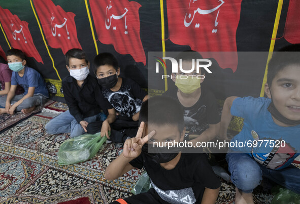 An Afghan refugee young boy wearing a protective face mask flashes a Victory sign while attending a Muharram mourning ceremony for praying f...