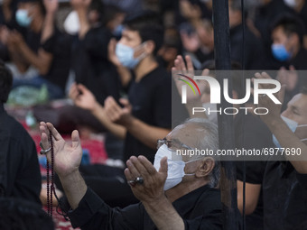 An Afghan refugee elderly man wearing a protective face mask reacts as he prays for peace and Afghanistan while attending a Muharram mournin...