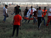 Palestinian protesters evacuate an injured youth amid clashes with Israeli security forces following a demonstration by the border fence wit...