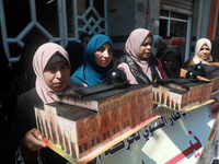 Palestinian women raise a sculpture of Al-Aqsa Mosque during a protest marking the anniversary of a 1969 arson attack at Jerusalem's Al-Aqsa...