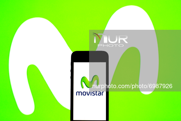 In this photo illustration a Movistar logo seen displayed on a smartphone with a Movistar logo in the background. 