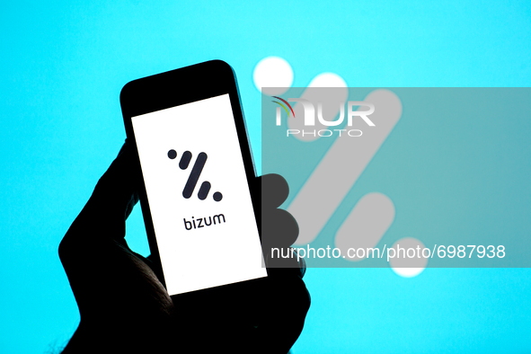 In this photo illustration a Bizum logo seen displayed on a smartphone with a Bizum logo in the background. 