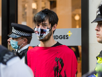 LONDON, UNITED KINGDOM - AUGUST 24, 2021: An environmental activist from Extinction Rebellion with face covered in fake oil protests outside...