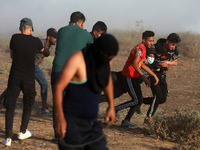 Palestinian protesters carry a wounded young man during a protest in the southern Gaza Strip August 25, 2021. 
 (