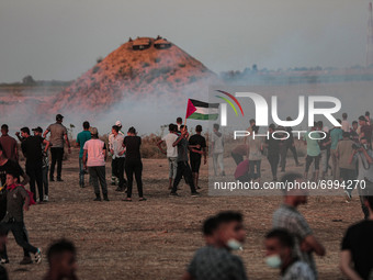 Protesters run and take cover from teargas fired by Israeli troops near the fence of Gaza Strip border with Israel during a protest east of...