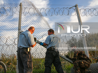 Hungarian soldiers and workers erect a barbwire fence as Hungarian police officers close the border line between Serbia and Hungary in Roszk...