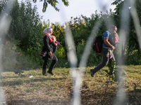 Refugees are walking along the barbed wire separating Hungary and Serbia at the border line in Roszke, southern Hungary on September 14, 201...
