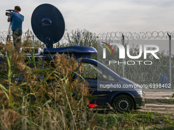 A journalist is working next to a barbwire fence at the border line between Serbia and Hungary in Roszke, southern Hungary on September 14,...