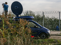 A journalist is working next to a barbwire fence at the border line between Serbia and Hungary in Roszke, southern Hungary on September 14,...
