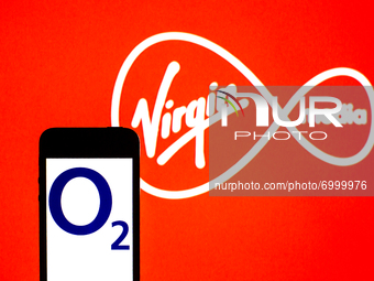 In this photo illustration a O2 logo seen displayed on a smartphone with a Virgin Media Inc logo in the background. (