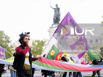 A Kurdish protester carries a flag bearing the effigy of three Kurdish activists killed in Paris, France, on August 28, 2021.As the French a...