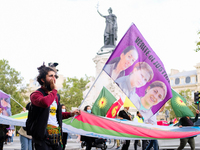 A Kurdish protester carries a flag bearing the effigy of three Kurdish activists killed in Paris, France, on August 28, 2021.As the French a...