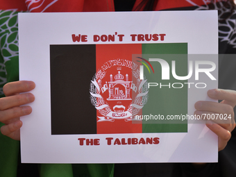 A protester holds a poster with a striped black-red-green national flag of Afghanistan with words 'We Don't Trust The Talibans'.
Members of...