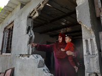A Palestinian woman inspects her house damaged in a nearby Israel bombing at Hamas sites over fire balloons into Israel, in Beit Hanoun in t...
