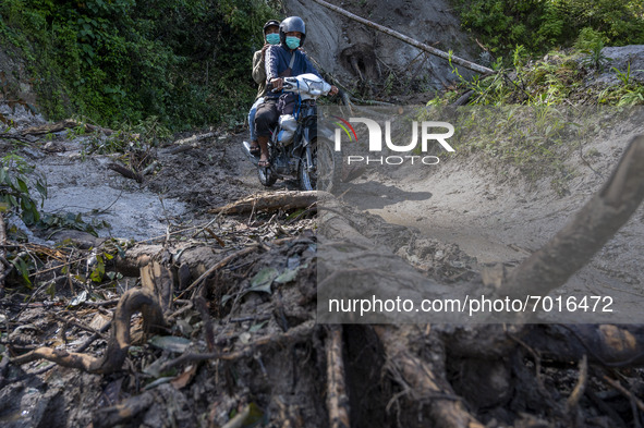 A motorist walks on the Trans Palu-Kulawi Road which is buried by landslide material in Namo Village, Sigi Regency, Central Sulawesi Provinc...