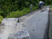 Residents carry a coffin crossing a road covered by landslide material on the Trans Palu-Kulawi road section in Salua Village, Sigi Regency,...
