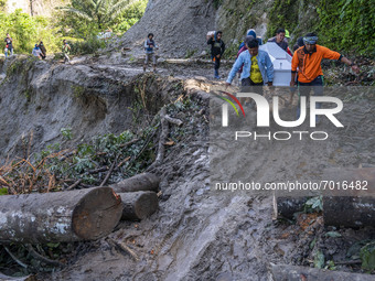 Residents carry a coffin crossing a road covered by landslide material on the Trans Palu-Kulawi road section in Salua Village, Sigi Regency,...
